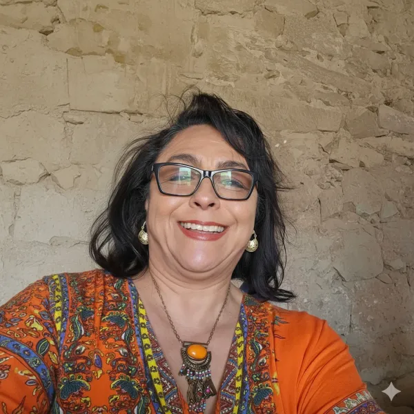 Dolores Castro Tate smiling with glasses against stone wall